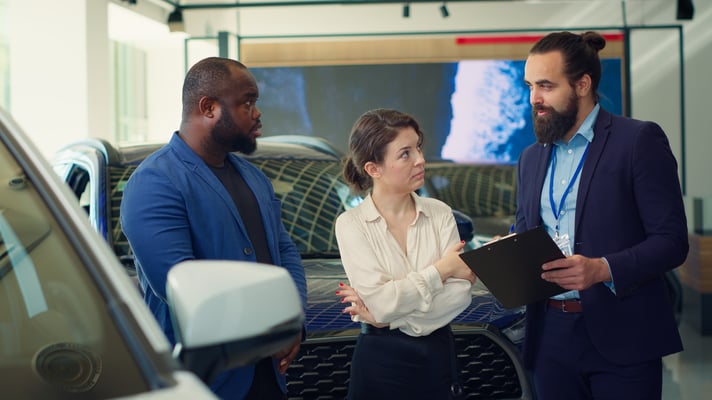 car-dealership-salesman-reading-clipboard-to-custo-2024-12-05-19-31-38-utc