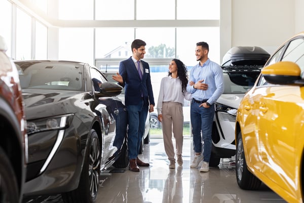 happy-couple-buying-car-at-dealership-with-salesma-2026-03-24-02-18-33-utc