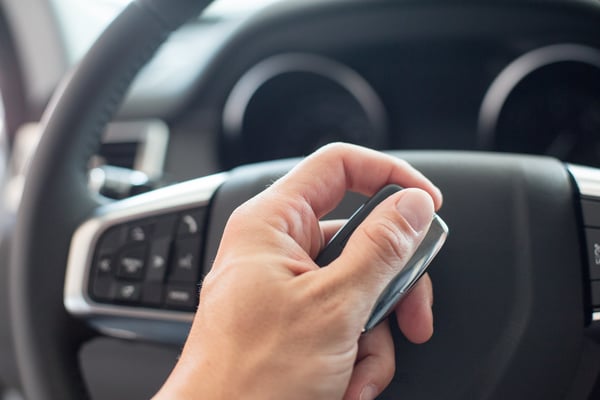 male-hand-holding-a-car-key-and-steering-wheel-6LFSVYE