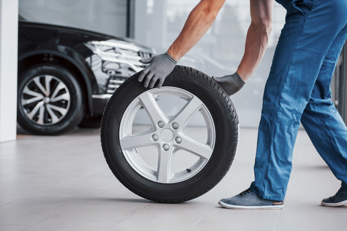 mechanic-holding-a-tire-tire-at-the-repair-garage--BBTJS9B