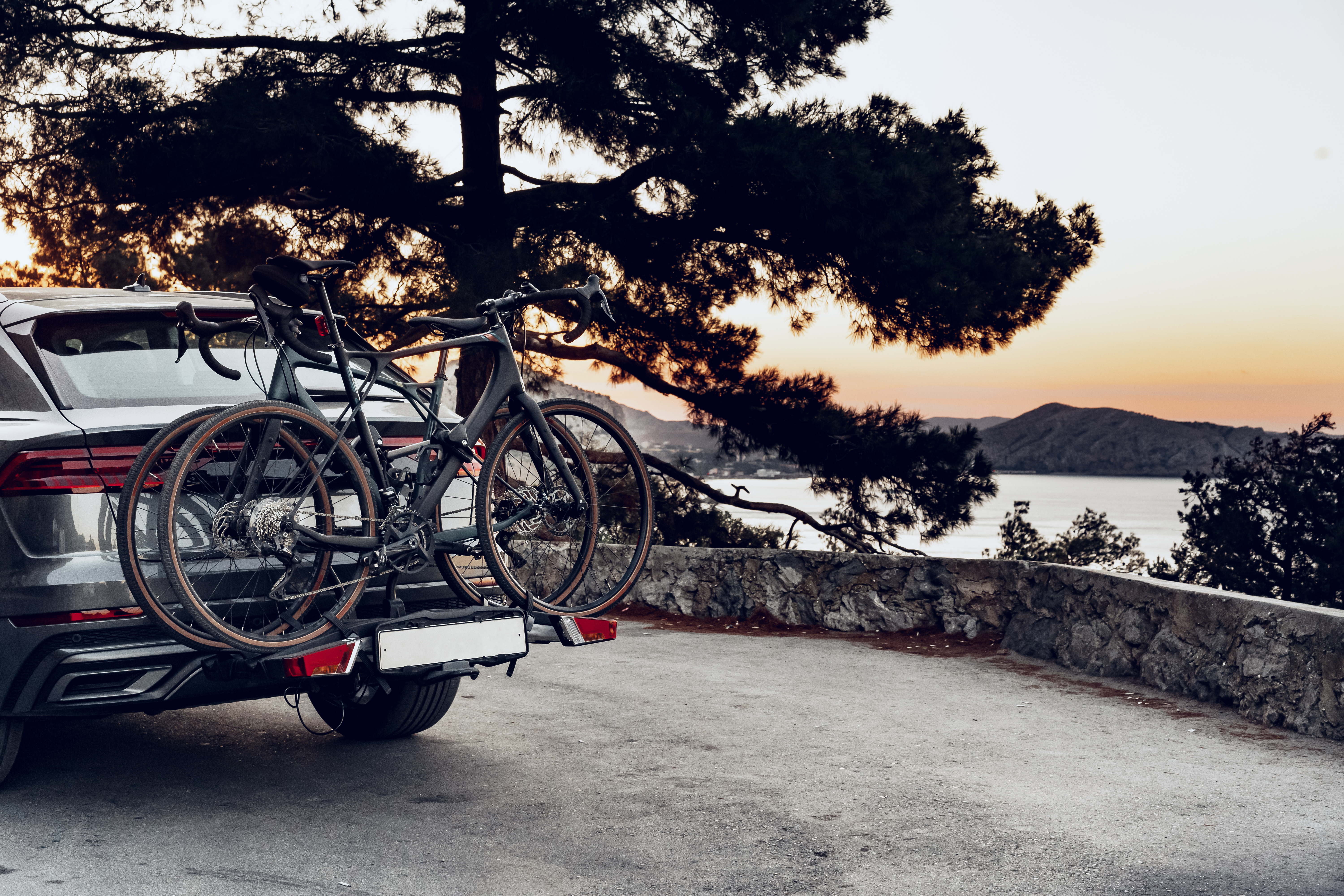 Vehicle with bikes mounted on the back against a serene outdoor background