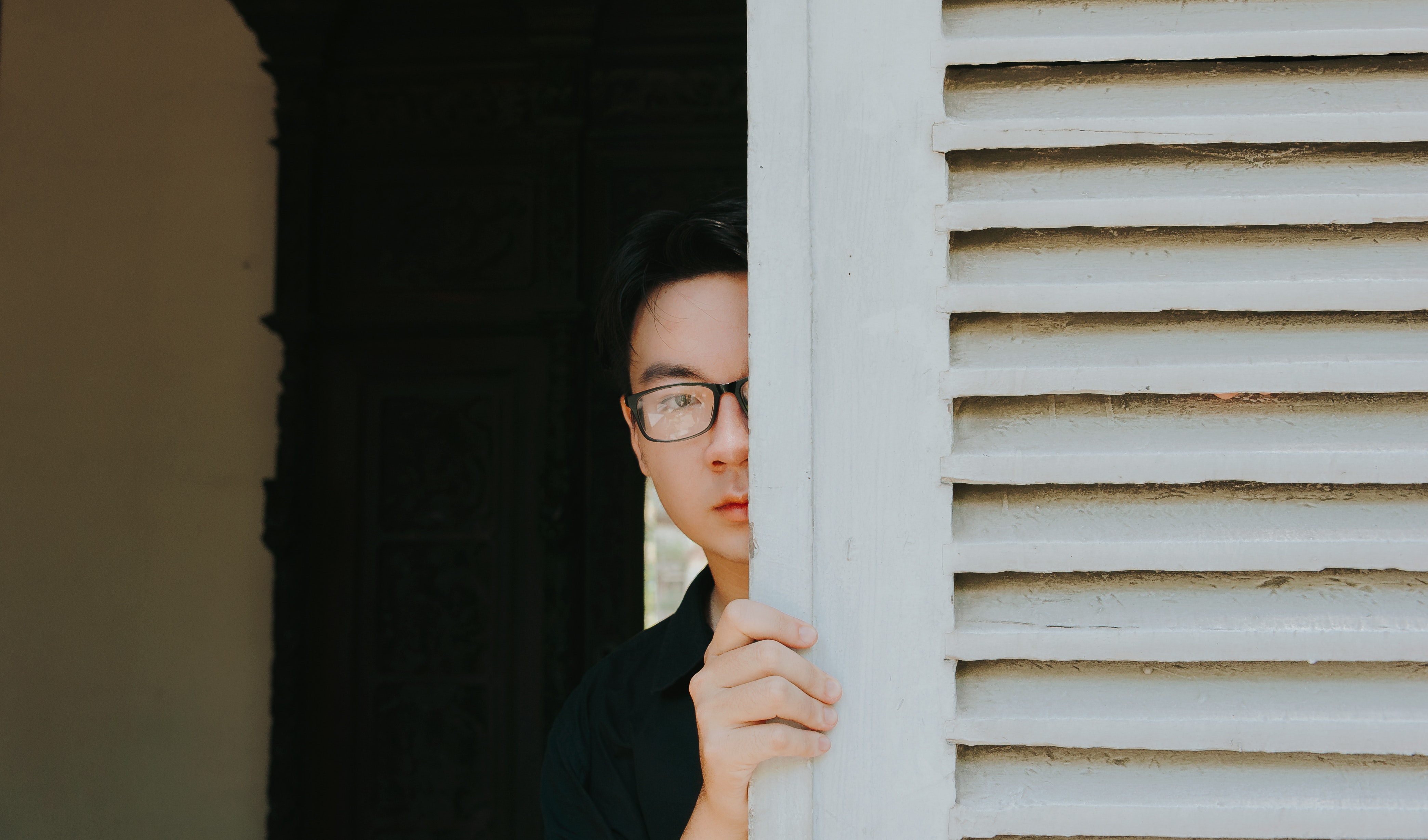 man hiding behind door